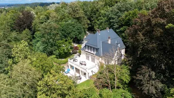 Beeindruckende Luftaufnahme des Anwesens, eingebettet in eine weitläufige grüne Landschaft mit Fernblick.