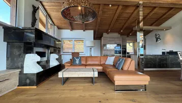 Geräumiger offener Wohnbereich mit Ledersofa, Holzbalkendecke und integrierter moderner Küche.
