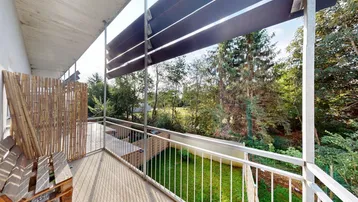 Geräumiger Balkon mit Blick ins Grüne und einem Sichtschutz aus Bambus.