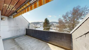 Geräumiger Balkon mit Markise und weitem Blick über eine verschneite Landschaft.