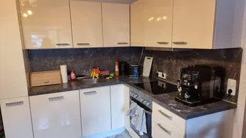 Moderne Küche mit cremefarbenen Hochglanzfronten, dunkler Arbeitsplatte und integriertem Kochfeld.