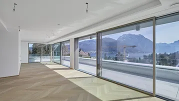 Helles Wohnzimmer mit Fischgrätparkett, großen Schiebetüren und beeindruckendem Bergblick.