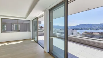 Helles Wohnzimmer mit großen Schiebetüren, Zugang zur Terrasse und Seeblick.