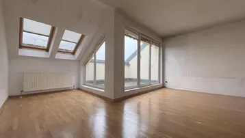 Helles Dachgeschosszimmer mit Parkettboden, Dachfenstern und Zugang zu einer Terrasse.