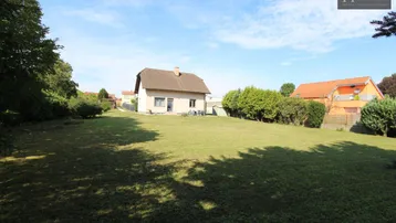 Weitläufiger Garten mit großer Rasenfläche und dem Einfamilienhaus im Hintergrund an einem sonnigen Tag.
