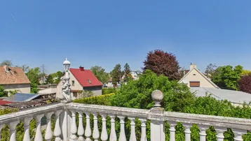 Sonnenterrasse mit Balustrade und Blick auf die umliegenden Häuser und Gärten.