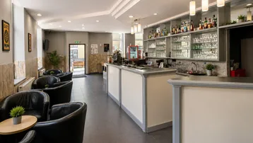 Bar- und Loungebereich mit dunklen Ledersesseln und einer gut ausgestatteten Theke.