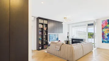 Helles Wohnzimmer mit modernem Sofa, Bücherregal und Blick ins Grüne.