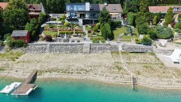 Luftaufnahme einer luxuriösen Villa mit weitläufigem Garten und privatem Seezugang mit Steg.