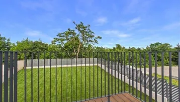 Blick vom Balkon auf den weitläufigen grünen Garten und die umliegende Natur.