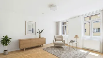 Helles Wohnzimmer mit modernem Holzsideboard, beigem Sessel und Parkettboden, lichtdurchflutet durch große Fenster.