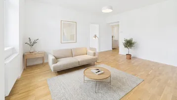 Helles Wohnzimmer mit modernem Sofa, Holzboden und Blick in den angrenzenden Raum.