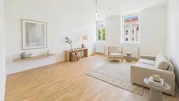 Helles Wohnzimmer mit Parkettboden, modernen Möbeln und Blick ins Grüne durch große Fenster.