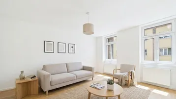 Helles Wohnzimmer mit modernem Sofa, Couchtisch und großen Fenstern für viel Tageslicht.