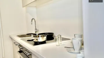 Moderne, kompakte Küchenzeile mit Induktionskochfeld und Spüle in weißem Design.