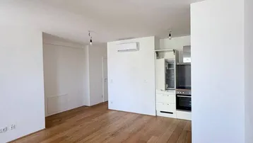 Helles, offenes Wohnzimmer mit Holzboden und integrierter Küchenzeile, ausgestattet mit Klimaanlage.