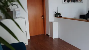 Heller Empfangsbereich mit Holzboden, weißer Einrichtung und einer blauen Couch.