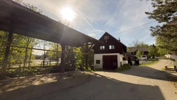 Gebäude mit Holzfassade und überdachtem Bereich unter strahlendem Sonnenschein.