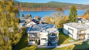 Moderne Wohnanlage mit Flachdach und Seeblick in herbstlicher Landschaft.