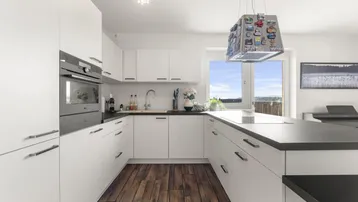 Moderne Küche mit weißen Schränken, dunkler Arbeitsplatte und Holzboden, bietet einen weiten Ausblick.