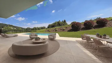 Großzügige Terrasse mit Pool und bequemen Lounge-Möbeln, umgeben von grüner Landschaft.