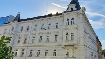 Elegantes weißes Gebäude mit klassischer Architektur und Mansarddach unter blauem Himmel.