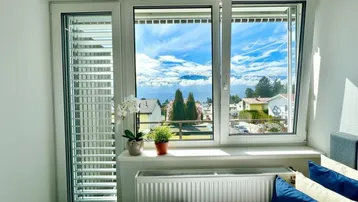 Schlafzimmer mit großem Fenster, das einen weiten Blick auf die Berge und die Umgebung bietet.