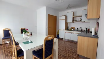 Heller offener Wohn-Essbereich mit integrierter Küche und Holzboden.