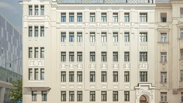 Klassische Fassade eines Stadthauses mit detaillierten Verzierungen und großen Fenstern.
