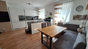 Moderne offene Küche mit Essbereich und angrenzendem Wohnbereich, ausgestattet mit Holzboden und viel Tageslicht.