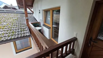 Kleiner Balkon mit Holzboden, Geländer und Blick auf die umliegende Landschaft.