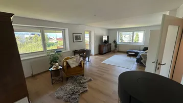 Lichtdurchfluteter Wohnbereich mit gemütlicher Sitzecke und Blick ins Grüne.