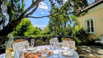 Einladender Esstisch auf der Terrasse, umgeben von üppigem Grün und mit Blick auf die Ferne.