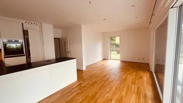 Heller offener Wohn- und Essbereich mit Holzboden und Zugang zur Terrasse und zum Garten.