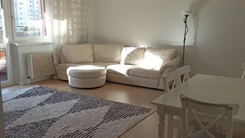 Heller Wohn- und Essbereich mit Parkettboden, weißer Einrichtung und Zugang zum Balkon.