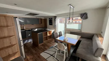 Offener Wohn-Essbereich mit moderner Küche, Holzboden und gemütlicher Sitzecke.