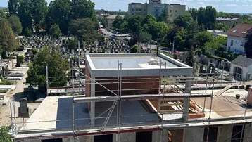 Luftaufnahme einer Baustelle mit umliegender Wohnbebauung und Friedhof.