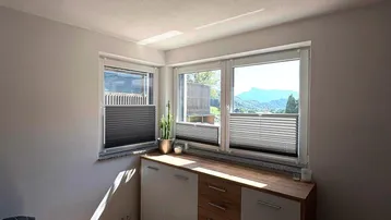 Helles Schlafzimmer mit Holzboden, modernen Möbeln und einem schönen Bergblick durch die Fenster.