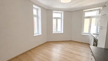Helles Zimmer mit Laminatboden, Stuckdecke und integrierter Küchenzeile in modernem Stil.