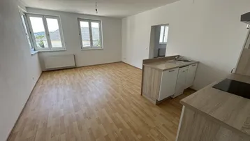 Geräumiger, heller Wohnbereich mit Laminatboden und Fenstern, die viel Tageslicht hereinlassen.