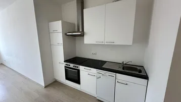 Kleine, moderne Küche mit weißen Schränken, schwarzer Arbeitsplatte und integrierten Geräten.