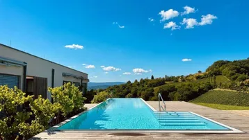 Infinity-Pool mit Holzdeck und weitem Blick über die Weinberge und die Landschaft.