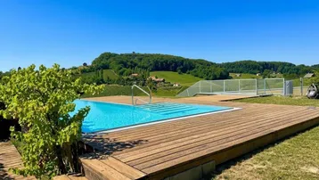 Großer Außenpool mit Holzdeck und weitem Blick über die umliegende Hügellandschaft und Weinberge.
