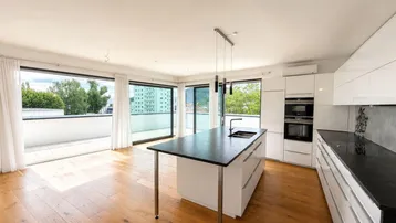 Moderne Küche mit Kochinsel, integrierten Geräten und großen Fenstern mit Terrassenzugang.