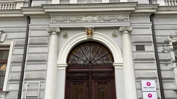 Repräsentativer Eingangsbereich eines historischen Gebäudes mit Holztür und dekorativen Elementen.