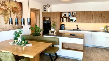Offener Wohn- und Essbereich mit moderner Holzküche, Esstisch und Weltkarte an der Wand.