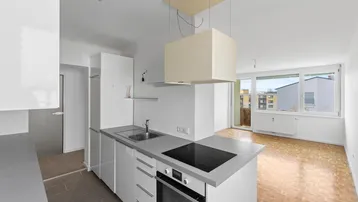 Moderne offene Küche mit Kochinsel, Induktionskochfeld und Blick in den angrenzenden Wohnbereich.