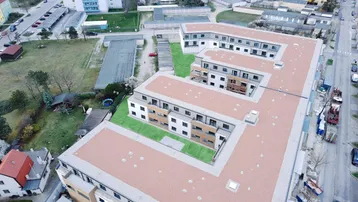 Luftaufnahme eines modernen Wohnkomplexes mit begrünten Innenhöfen und umliegender Bebauung.