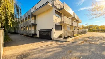 Modernes Mehrfamilienhaus mit Balkonen und gepflegter Außenanlage unter blauem Himmel.
