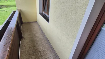 Balkon mit Holzbalken und Fliesenboden bietet einen weiten Blick ins Grüne.